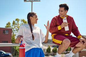 A guy and a girl talking and smiling and holding Owala water bottles